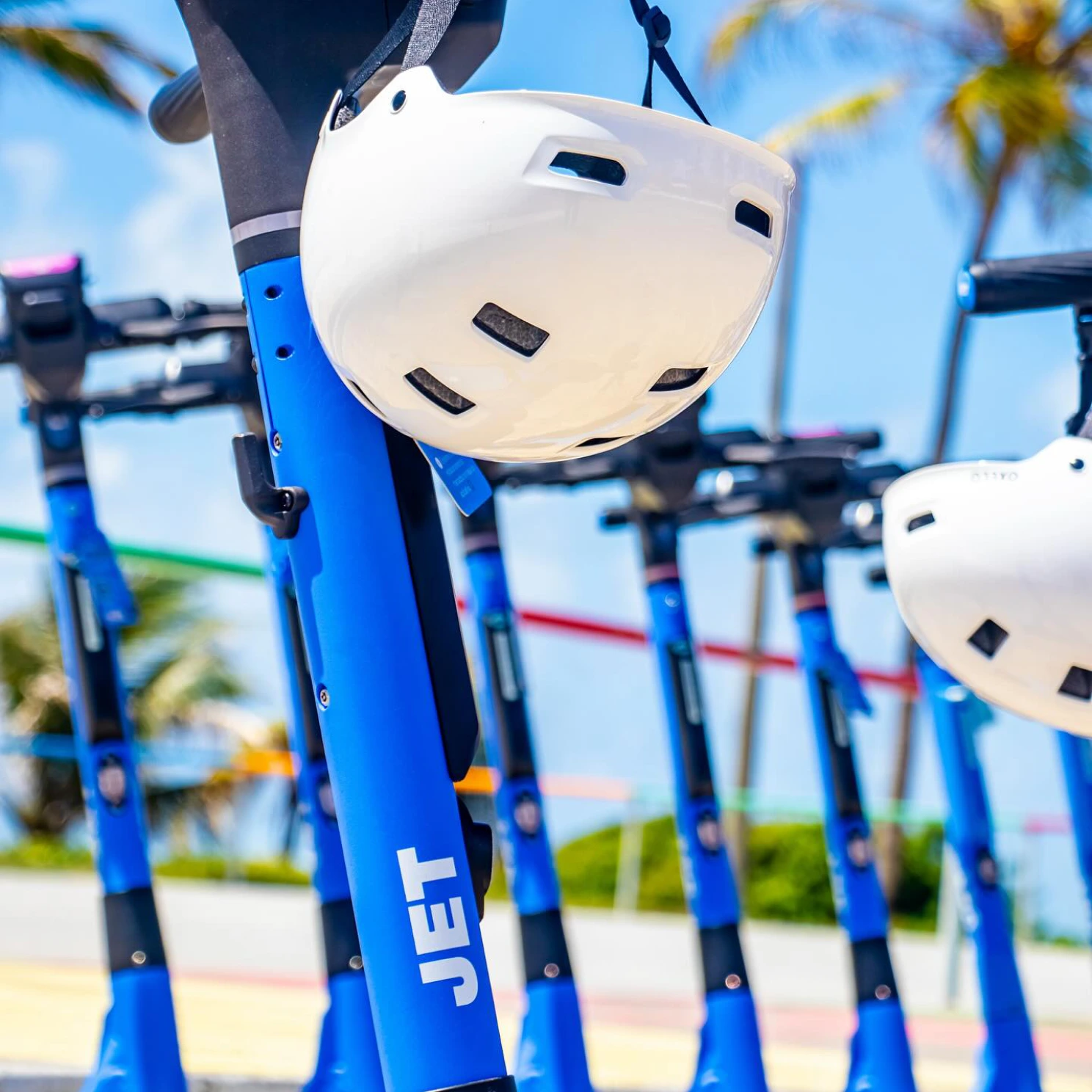 JET e-scooters with white helmets parked by the beach